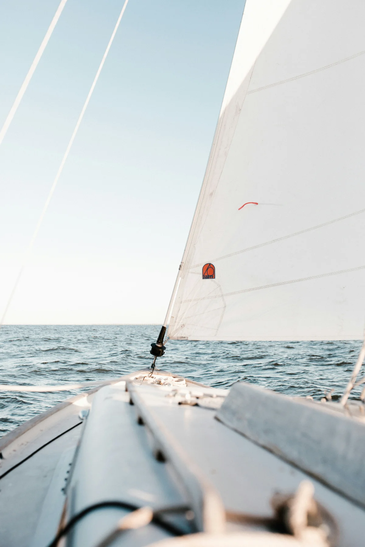 White sail above the open sea, viewed from a sailing boat