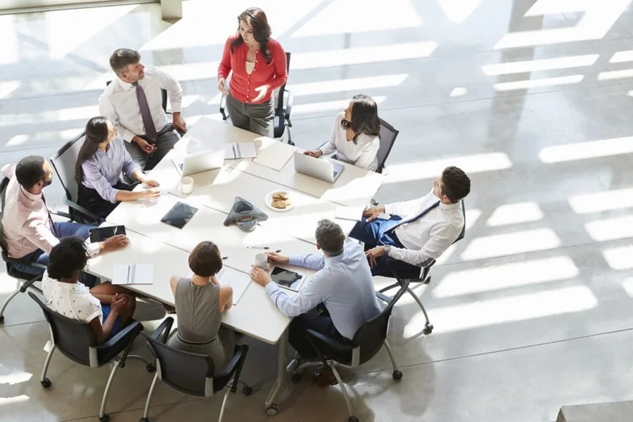 A team meeting around a table in a sunlit office, seen from above